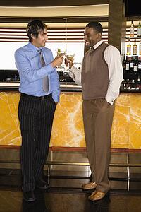 Two men toasting martinis at bar
