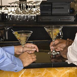 Male hands holding martinis at bar