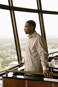Side view of mid adult man in tower restaurant looking out window at view