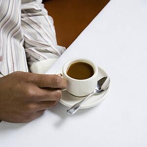 African American male hand holding handle of expresso cup.