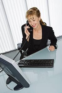Businesswoman at computer desk on telephone