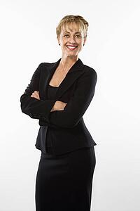 Caucasian businesswoman standing with arms crossed smiling at viewer.