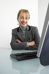 Woman looking at computer and smiling with arms crossed