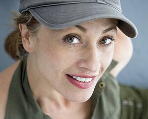 Caucasian woman wearing hat smiling at viewer.
