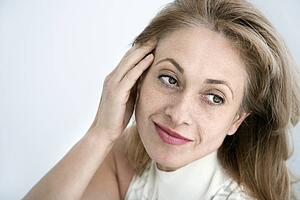 Woman with hand to head looking away