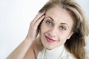 Attractive woman with hand to face smiling at viewer