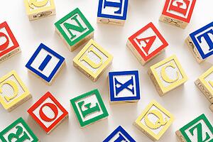 Alphabet building block scattered on white background.