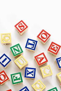 Alphabet building block scattered on white background.