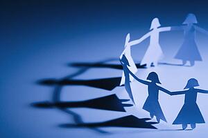 Cutout paper females standing holding hands.
