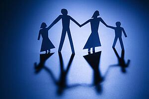 Paper cutout family of four standing holding hands.