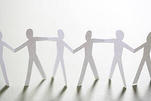 Cutout paper men standing holding hands.