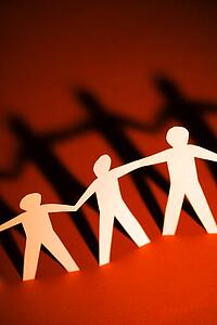 Cutout paper men standing holding hands.