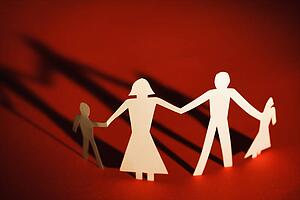 Paper cutout family of four standing holding hands