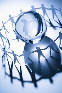 Cutout paper people standing around globe holding hands