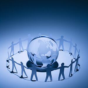 Cutout paper people standing around globe holding hands