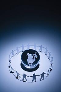 Cutout paper people standing around globe holding hands