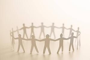 Cutout paper people standing in circle holding hands