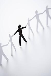One black cutout paper person holding hands with group of white people