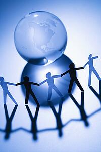 Black and white cutout paper people standing around Earth globe holding hands