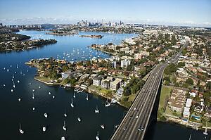 Aerial view of Victoria Road bridge and boats with distant downtown skyline in Sydney, Australia