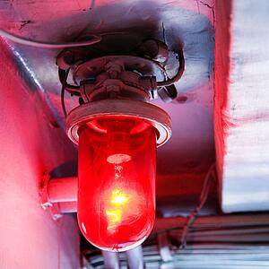 Red light bulb glowing from rustic fixture