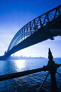 Low angle view of Sydney Harbour Bridge at dusk with harbour and distant Sydney skyline, Australia