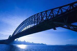 Sydney Harbour Bridge at dusk with view of distant skyline and harbour in Sydney, Australia.