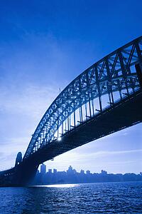 Sydney Harbour Bridge at dusk with view of distant skyline and harbour in Sydney, Australia.