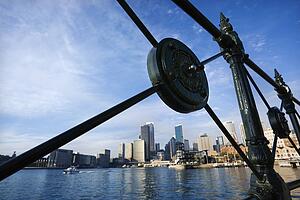 View of Sydney Cove from behind decorative iron railing with city skyline and water in Sydney, Australia