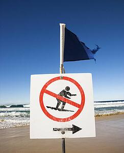 No surfing sign and flag on beach at Surfers Paradise, Australia.