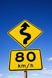 Kilometer per hour speed limit and curve ahead road signs in rural Australia