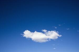 Single white fluffy cloud in blue sky