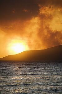 Sun setting over island with ocean