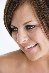 Bare Caucasian mid adult brunette woman looking to side and smiling.