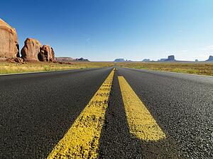 Open highway in scenic desert landscape with distant mountains and butte land formations