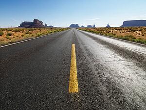 Open highway in scenic desert landscape with distant mountains and mesas