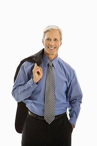 Man in business suit smiling at viewer with jacket draped over shoulder