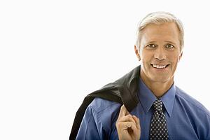 Man in business suit smiling at viewer with jacket draped over shoulder