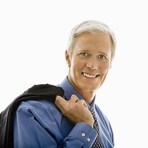 Man in business suit smiling at viewer with jacket draped over shoulder