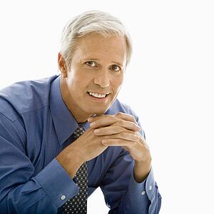 Man with hands folded in front smiling at viewer
