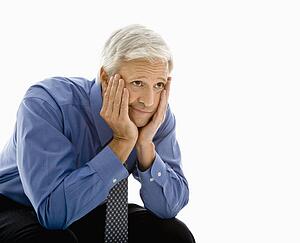 Middle aged man with head resting in hands looking bored
