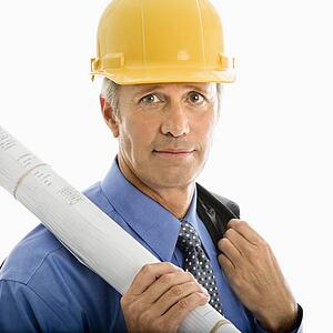 Caucasian middle aged businessman holding blueprints and wearing hard hat.