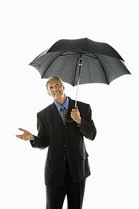 Businessman holding umbrella and gesturing