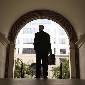 Businessman silhouette standing in archway holding briefcase