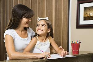 Mother helping daughter making eye contact and working on homework