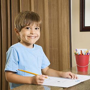 Boy smiling and doing homework