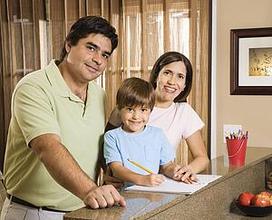 Hispanic parents and son with homework smiling at viewer.