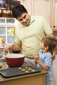 Hispanic father and son in kitchen making cookies.