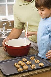 Father and son in kitchen making cookies