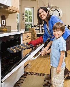 Mother and son putting cookies into oven